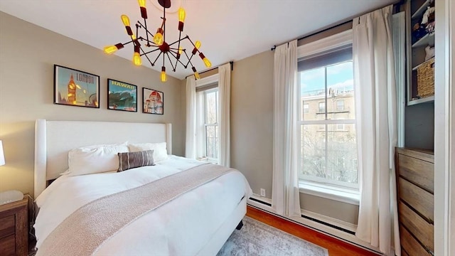 bedroom featuring wood finished floors, multiple windows, and an inviting chandelier