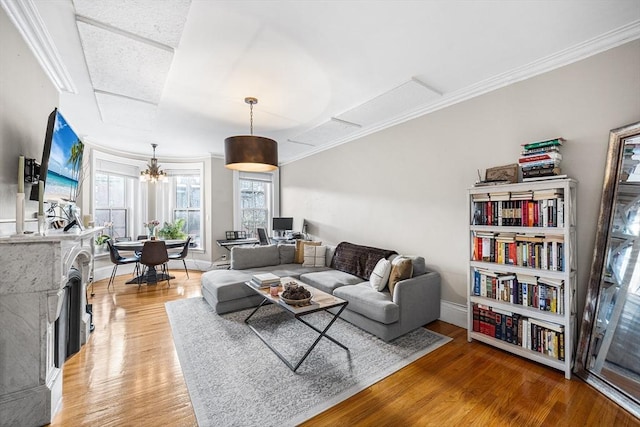 living room featuring light wood-style flooring, baseboards, ornamental molding, and an inviting chandelier