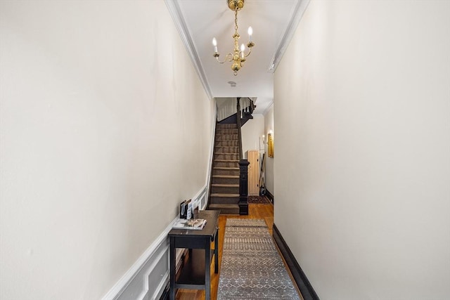 hall with wood finished floors, a notable chandelier, stairway, and crown molding