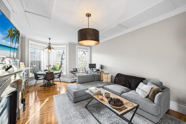 living area with ornamental molding, baseboards, a healthy amount of sunlight, and light wood-style flooring