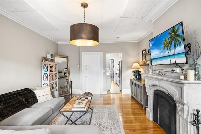 living area featuring light wood-style flooring, crown molding, and baseboards
