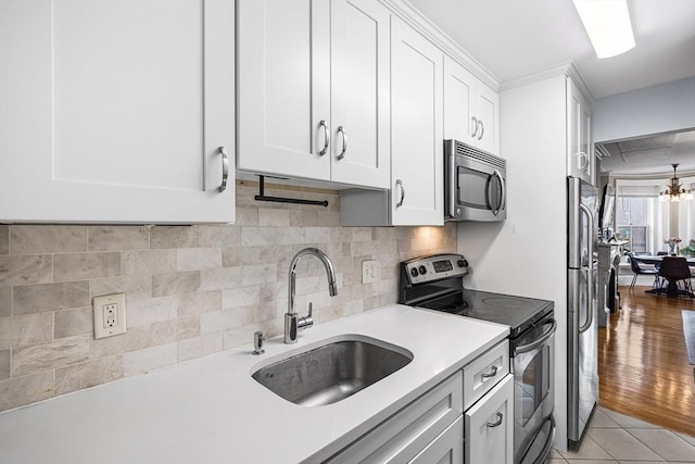 kitchen featuring white cabinets, appliances with stainless steel finishes, a sink, and light countertops