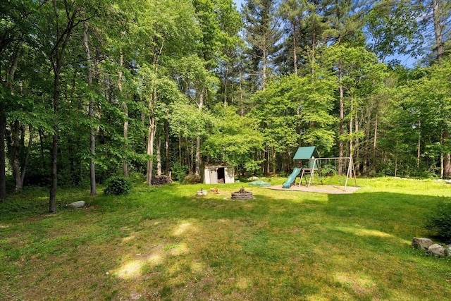 18 Arend Cir, Hanover, MA 02339 - view of grassy yard featuring a playground, a fire pit, and a wooded view