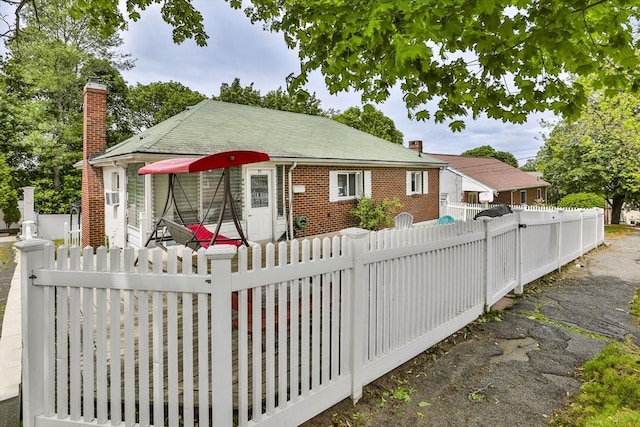 35 Linden Ter, Lynn, MA 01902 - view of front of house featuring a chimney, brick siding, a fenced front yard, and cooling unit