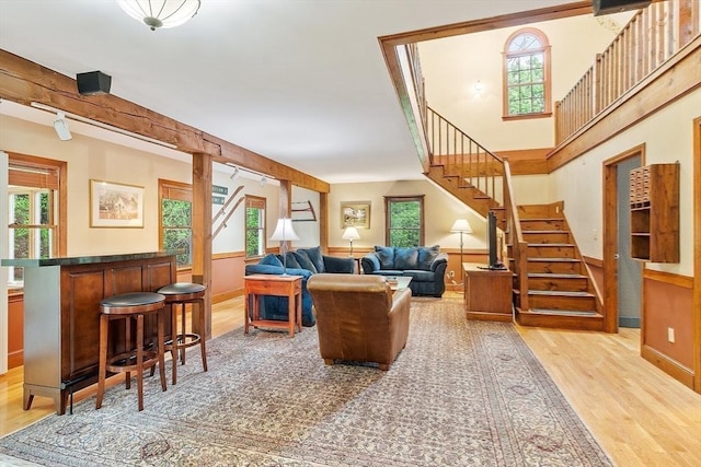 living room featuring light wood finished floors, stairway, and baseboards