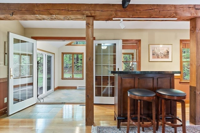 indoor dry bar featuring vaulted ceiling, wood-type flooring, healthy amount of natural light, a baseboard heating unit, and rail lighting