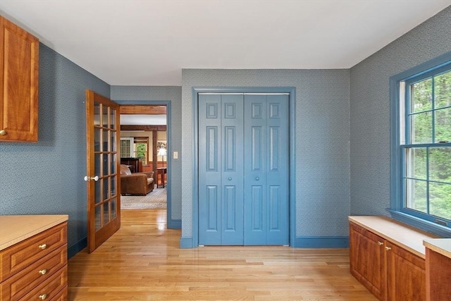 unfurnished bedroom with light wood-style floors, french doors, and a closet