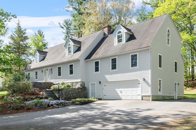 rear view of property with driveway, a garage, and a chimney