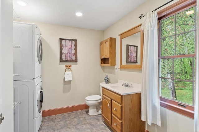 bathroom with stacked washer / dryer, baseboards, toilet, vanity, and recessed lighting