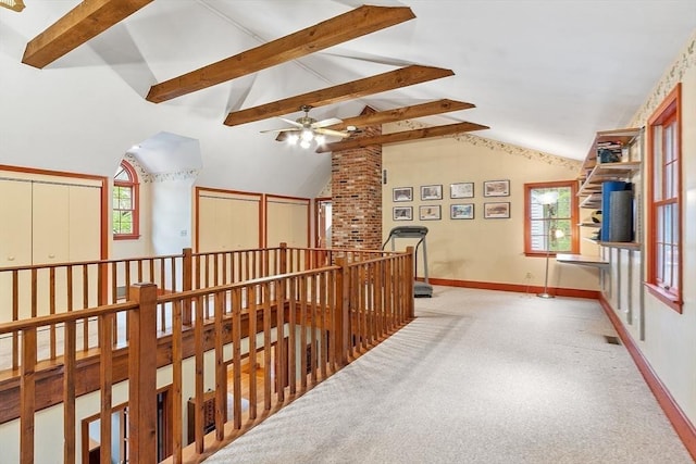 hall with plenty of natural light, beamed ceiling, baseboards, carpet flooring, and an upstairs landing