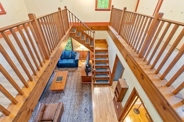 stairway with a towering ceiling and wood finished floors