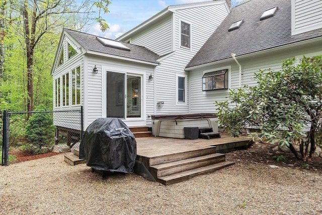 back of house with a hot tub, roof with shingles, a wooden deck, fence, and a chimney