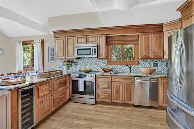 10 Eagles Nest, Edgartown, MA 02539 - kitchen with appliances with stainless steel finishes, wine cooler, a peninsula, brown cabinetry, and light stone counters