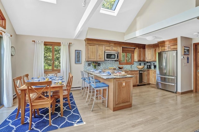 10 Eagles Nest, Edgartown, MA 02539 - kitchen featuring appliances with stainless steel finishes, a skylight, a kitchen bar, backsplash, and light wood-style flooring