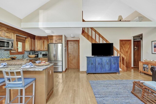 10 Eagles Nest, Edgartown, MA 02539 - kitchen with stainless steel appliances, lofted ceiling, brown cabinets, light wood-type flooring, and decorative backsplash