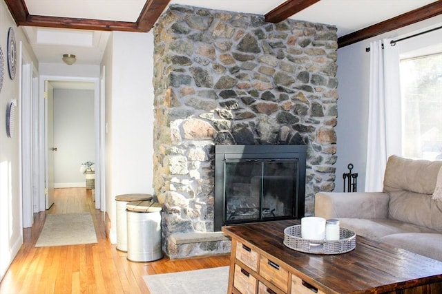 living room featuring a fireplace, beamed ceiling, and light wood-type flooring