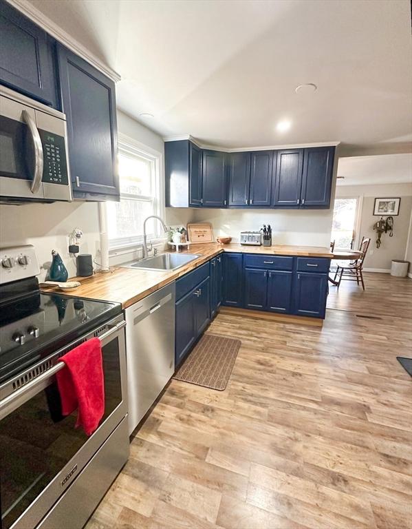 kitchen featuring wooden counters, blue cabinets, sink, appliances with stainless steel finishes, and light hardwood / wood-style floors