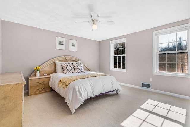 bedroom with light carpet, visible vents, a ceiling fan, and baseboards