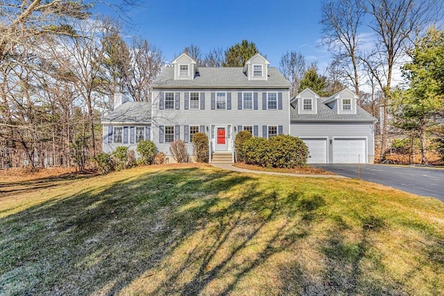 colonial home with aphalt driveway, a garage, and a front lawn