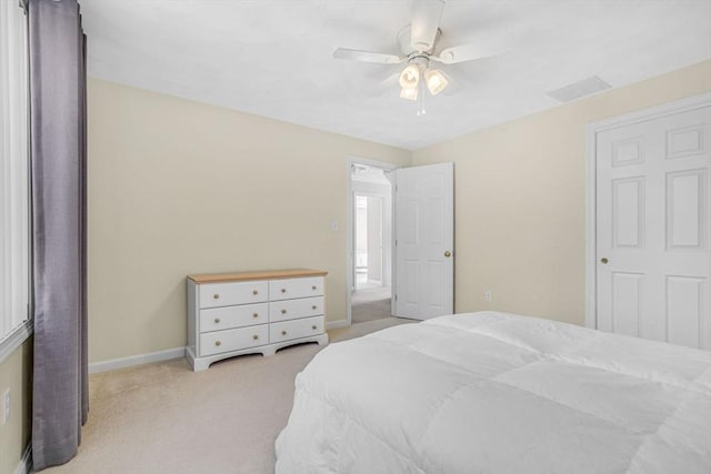 bedroom with visible vents, light colored carpet, baseboards, and ceiling fan