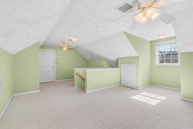 bonus room with lofted ceiling, baseboards, visible vents, and a textured ceiling