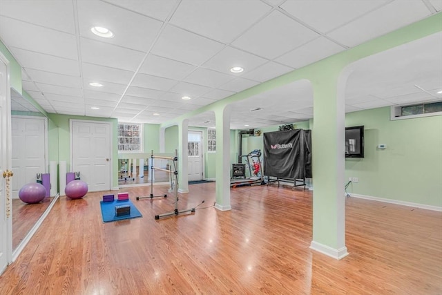 workout room with recessed lighting, a paneled ceiling, baseboards, and wood finished floors