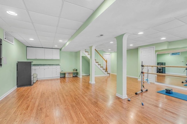 workout area featuring recessed lighting, a drop ceiling, light wood-style flooring, and baseboards