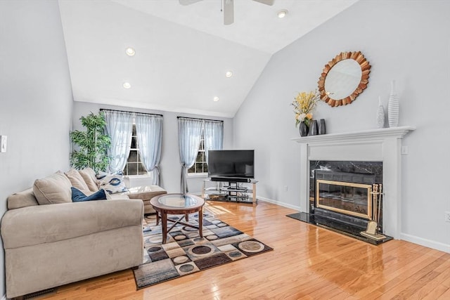 living area with a high end fireplace, baseboards, lofted ceiling, and wood finished floors