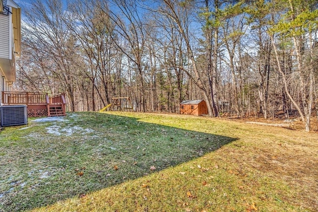 view of yard featuring a wooden deck, central air condition unit, a storage unit, and an outdoor structure