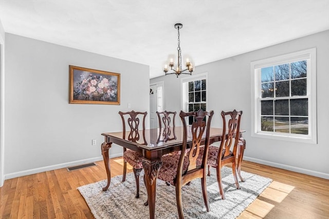 dining room with visible vents, baseboards, light wood-style floors, and an inviting chandelier