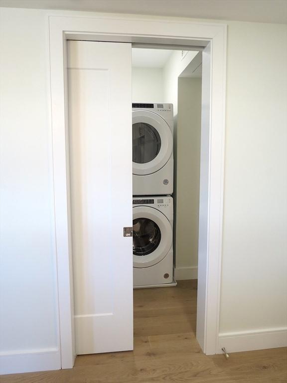 301 Border Unit 409, Boston, MA 02128 - laundry area with stacked washing machine and dryer, light wood-style flooring, and baseboards