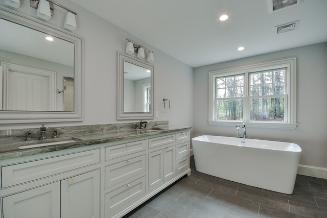 bathroom with double vanity, tile floors, and a bathtub