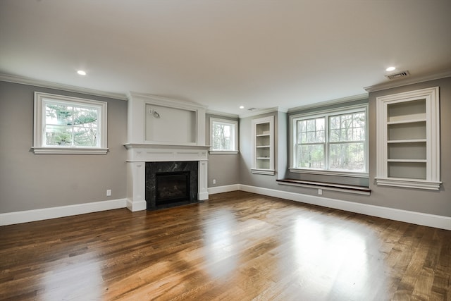 unfurnished living room featuring a high end fireplace, a healthy amount of sunlight, hardwood / wood-style flooring, and ornamental molding