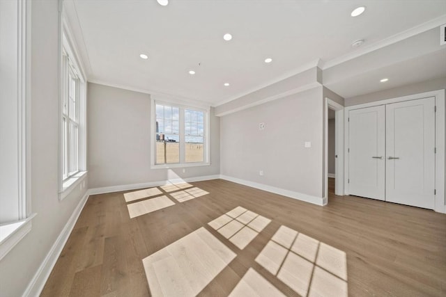 spare room with crown molding, wood finished floors, and baseboards