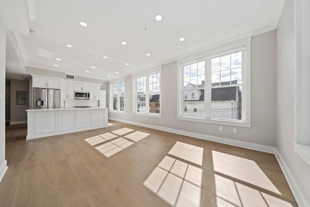 unfurnished living room with crown molding, light wood-style floors, and baseboards