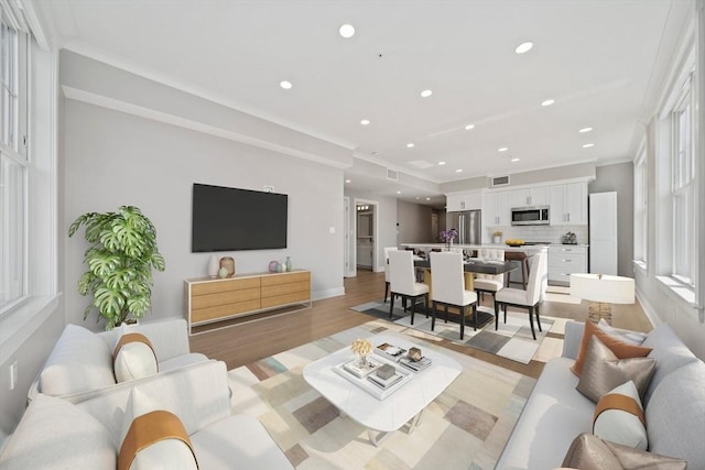 living area featuring recessed lighting, baseboards, light wood-style floors, and ornamental molding