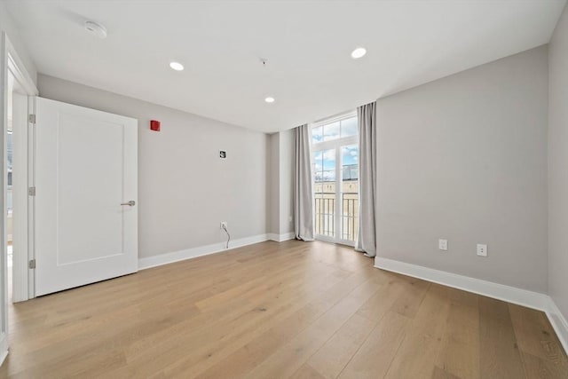 unfurnished room with floor to ceiling windows, recessed lighting, light wood-type flooring, and baseboards