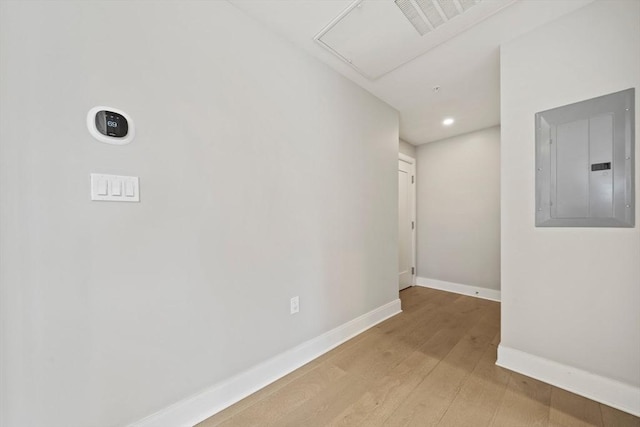 empty room with electric panel, baseboards, and wood finished floors