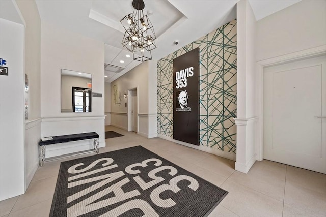 tiled entryway featuring a raised ceiling, a notable chandelier, and recessed lighting