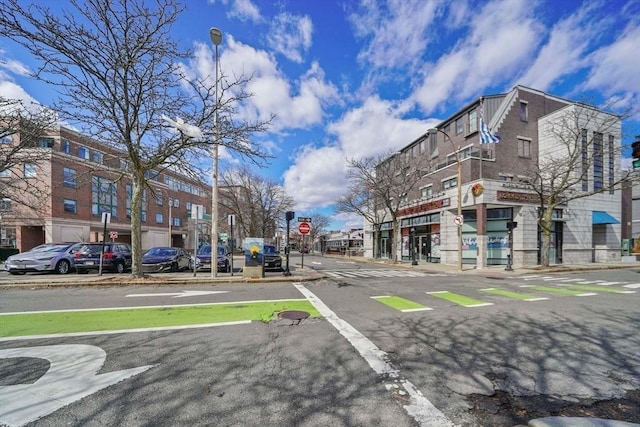 view of road featuring traffic signs, curbs, street lighting, and sidewalks