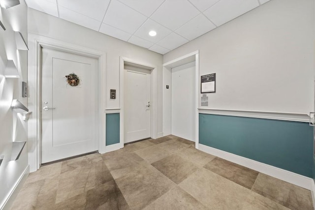 foyer featuring a drop ceiling and baseboards