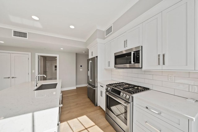 kitchen featuring visible vents, stainless steel appliances, decorative backsplash, and a sink