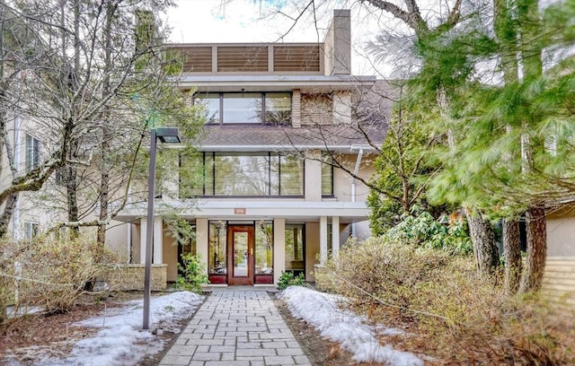 view of front of house featuring french doors, a chimney, and stucco siding