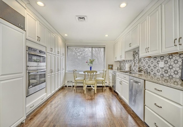 kitchen featuring tasteful backsplash, visible vents, appliances with stainless steel finishes, white cabinets, and wood finished floors