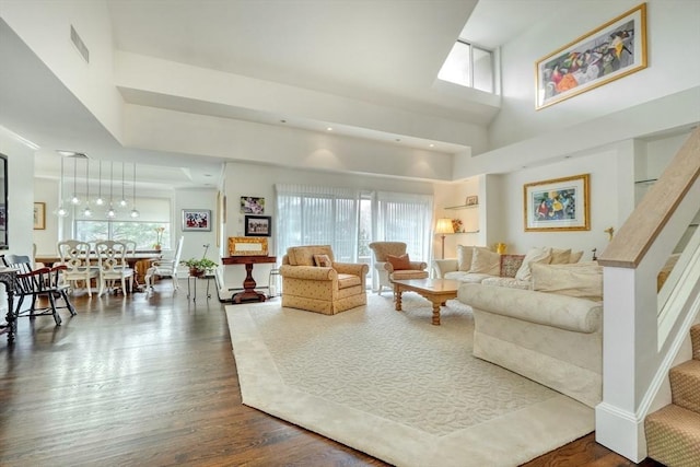 living area featuring plenty of natural light, a high ceiling, visible vents, and dark wood-style flooring