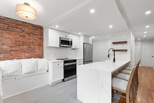 117 Fulton St Unit 4, Boston, MA 02109 - kitchen featuring appliances with stainless steel finishes, white cabinets, tasteful backsplash, a peninsula, and crown molding