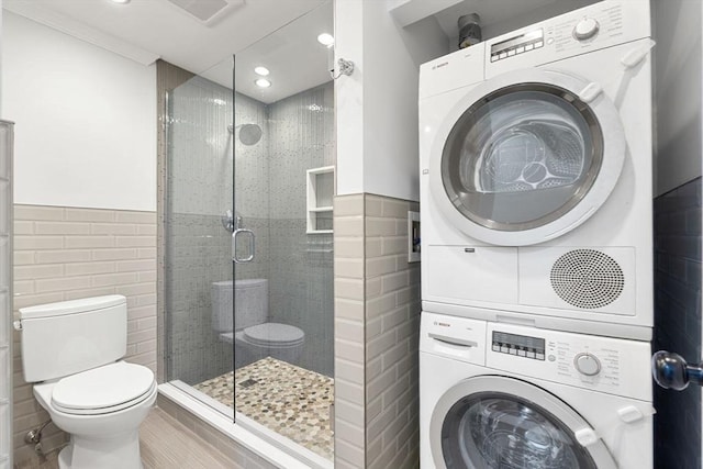 117 Fulton St Unit 4, Boston, MA 02109 - bathroom featuring stacked washing machine and dryer, tile walls, a stall shower, recessed lighting, and wainscoting