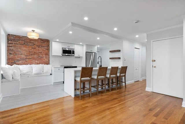 117 Fulton St Unit 4, Boston, MA 02109 - kitchen with stainless steel appliances, ornamental molding, light wood finished floors, a kitchen breakfast bar, and white cabinetry