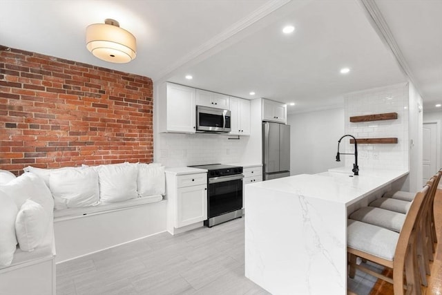 117 Fulton St Unit 4, Boston, MA 02109 - kitchen featuring appliances with stainless steel finishes, white cabinetry, ornamental molding, decorative backsplash, and a peninsula