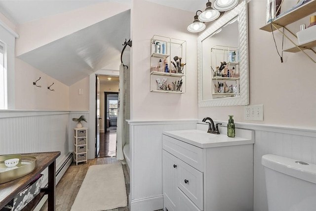 bathroom featuring baseboard heating, toilet, vanity, hardwood / wood-style flooring, and lofted ceiling